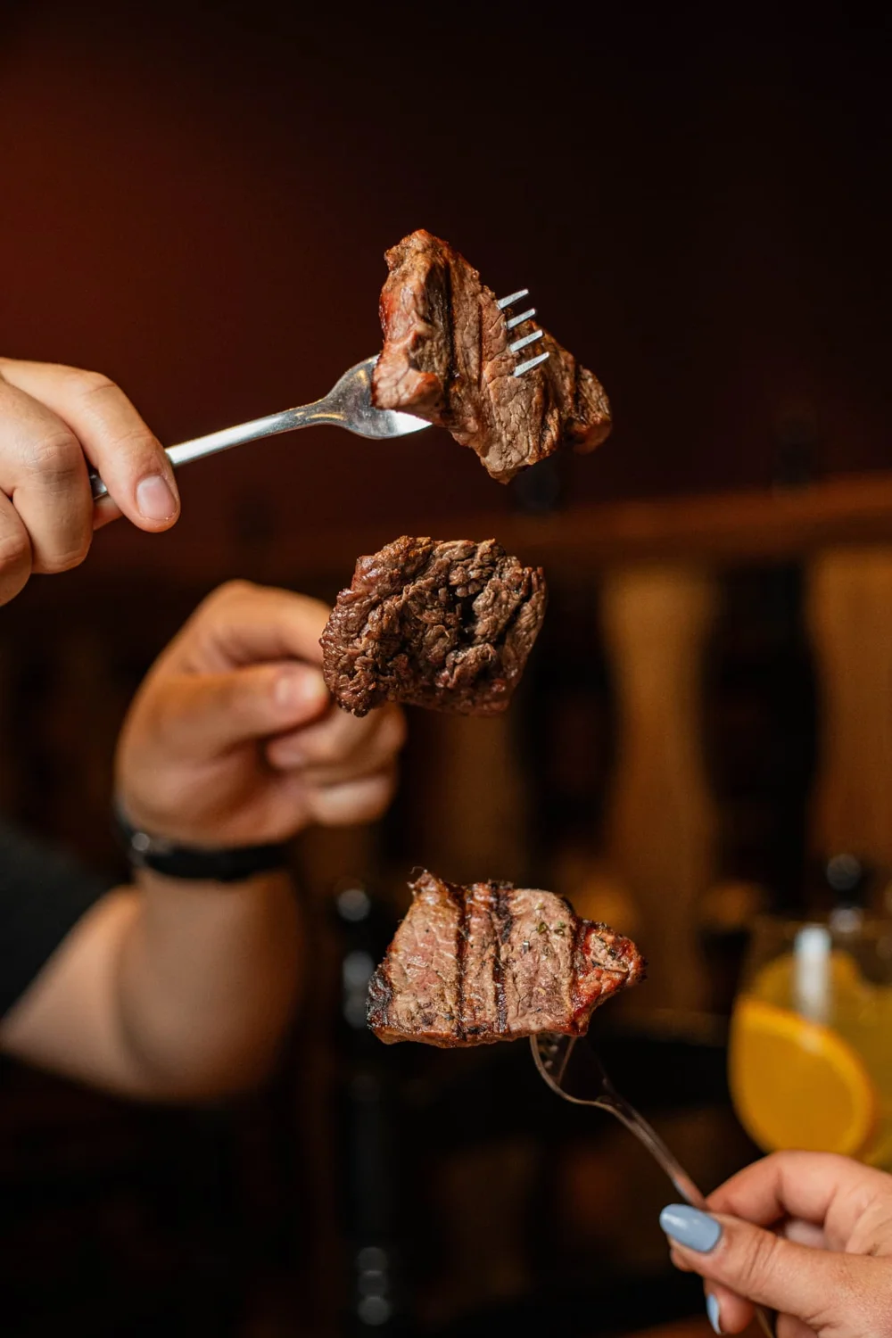 Tres personas brindan con sus cortes favoritos de carne
